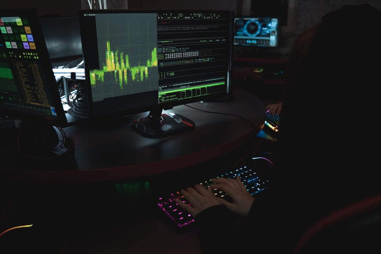 Um monitor, teclado e uma pessoa digitando algo.